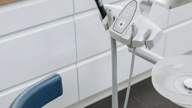 Mocho azul e painel de instrumentos ao lado da cadeira num consultório odontológico claro